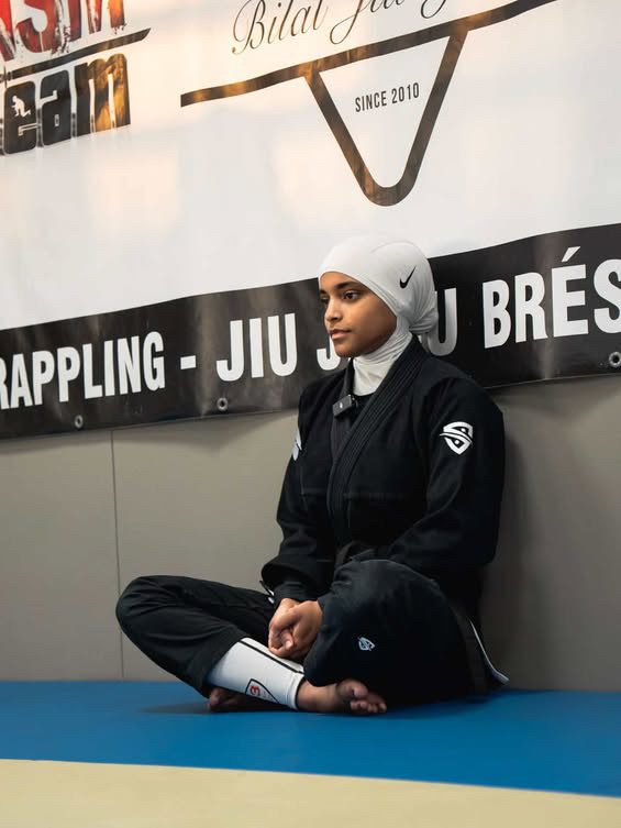 Sana Ndiaye assise sur le tapis du club NSM, en kimono noir, devant la bannière du club.