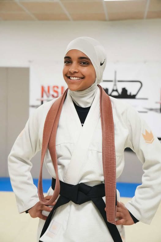 Sana Ndiaye en kimono blanc, ceinture noire nouée et ancienne ceinture marron posée sur les épaules, le jour de sa remise de grade.